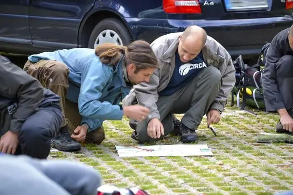 Zwei Personen betrachten eine Karte auf dem Boden, während sie knien