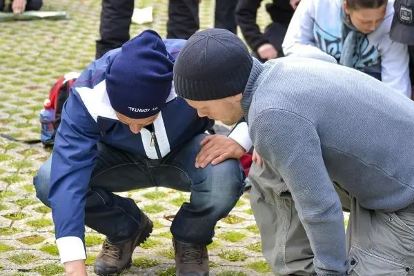 Zwei Personen beugen sich über den Boden und untersuchen etwas