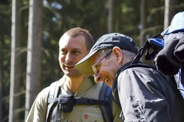 Zwei Personen stehen im Wald und lachen miteinander