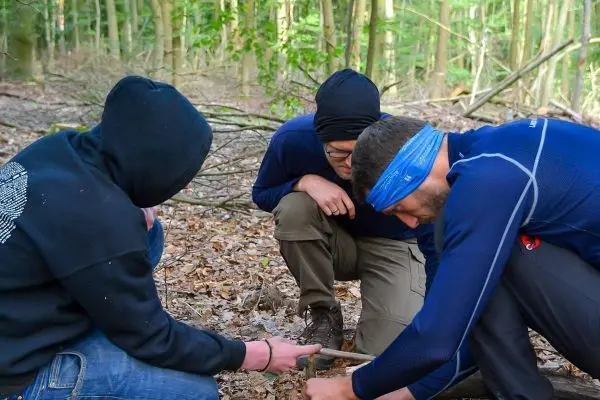 Drei Personen beugen sich über den Boden und untersuchen eine Feuerstelle