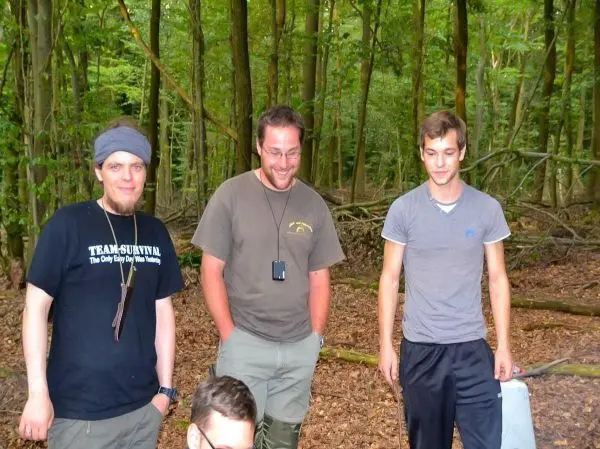 Drei Personen stehen im Wald und unterhalten sich