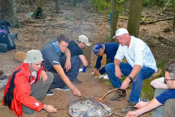 Gruppe bereitet Essen über einem kleinen Feuer im Wald