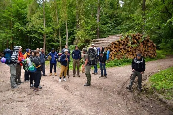 Gruppe mit Rucksäcken steht an einer Weggabelung im Wald