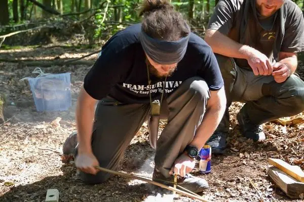 Holzstück wird mit einem anderen Stock bearbeitet, um Glut zu erzeugen