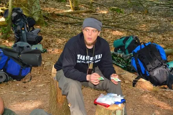 Mann sitzt auf einem Baumstumpf und hält Materialien in den Händen