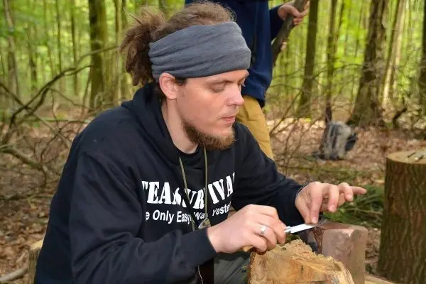 Messer bearbeitet Holzstück auf einem Baumstumpf im Wald