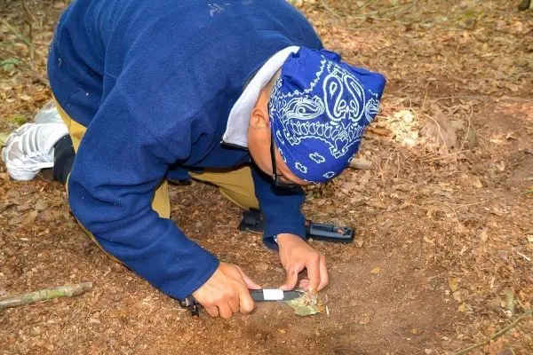 Messer schneidet Zunder auf dem Waldboden