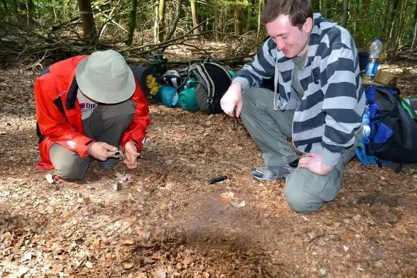 Zunder wird mit einem Messer bearbeitet, während ein anderer Teilnehmer beobachtet