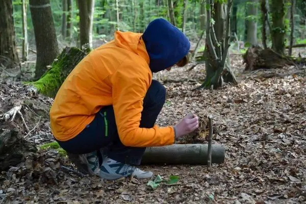 Zunder wird mit einem Stock auf einem Baumstamm bearbeitet