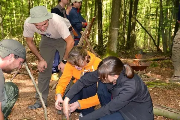 Zwei Personen bauen eine Konstruktion aus Ästen im Wald