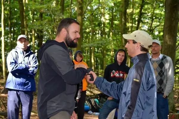 Zwei Personen schütteln sich die Hände, während andere zuschauen im Wald