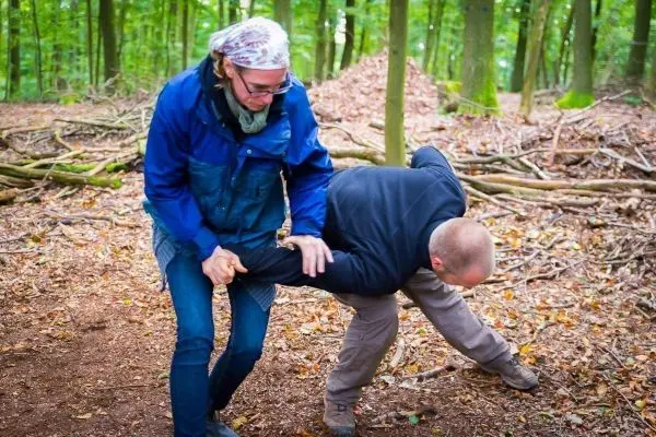 Eine Person hält einen anderen am Arm in einem Waldgebiet