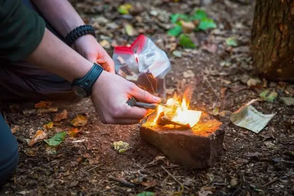 Feuerstahl entzündet Zunder auf einem Stein im Wald