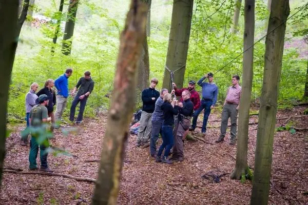 Gruppe übt den Aufbau einer selbstgebauten Seilbrücke im Wald