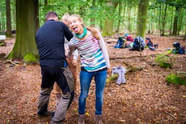 Gruppendynamik im Wald mit Rucksäcken im Hintergrund und zwei Personen in Interaktion