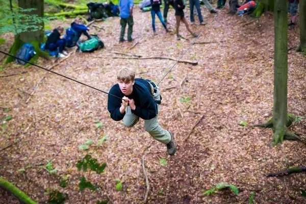 Junge überquert selbstgebaute Seilbrücke im Wald