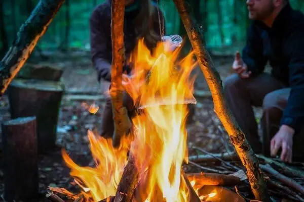Kleine Flamme brennt unter einem hängenden Topf über dem Feuer