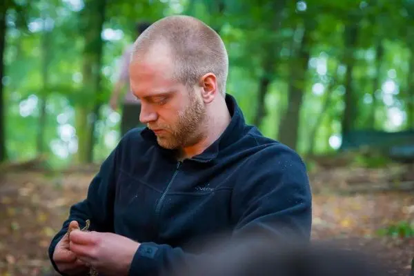 Mann bearbeitet ein Stück Holz im Wald