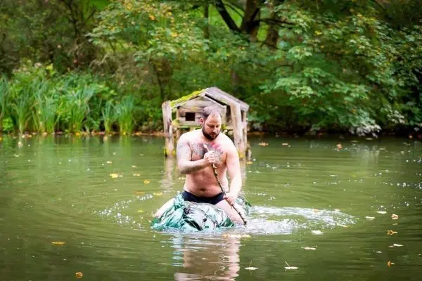 Mann paddelt auf improvisiertem Floß in einem Gewässer