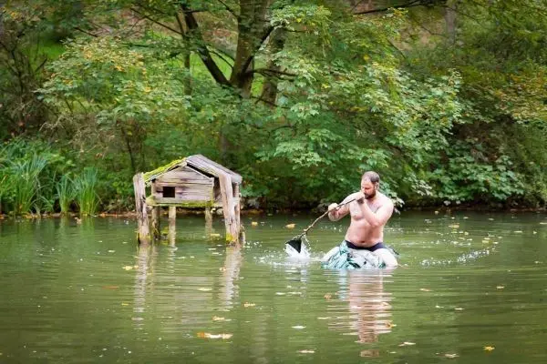 Mann paddelt mit einem improvisierten Paddel in einem Gewässer