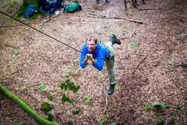 Mann überquert eine selbstgebaute Seilbrücke im Wald