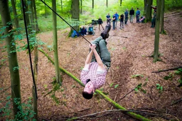 Mann überquert mit Seil eine Waldlichtung