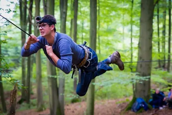 Mann überquert selbstgebaute Seilbrücke im Wald