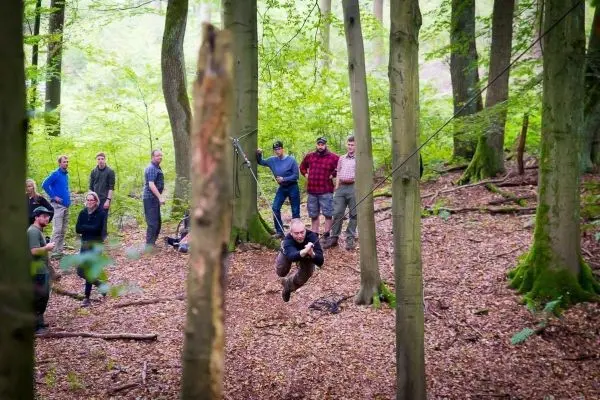 Mann überquert selbstgebaute Seilbrücke zwischen Bäumen im Wald