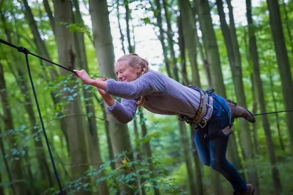 Seilquerung mit gesichertem Gurt und gespanntem Seil im Wald