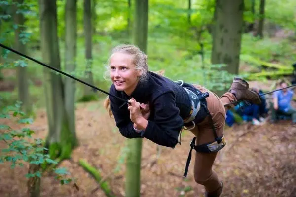 Selbstgebaute Seilquerung wird von einer Person in Kletterausrüstung überquert