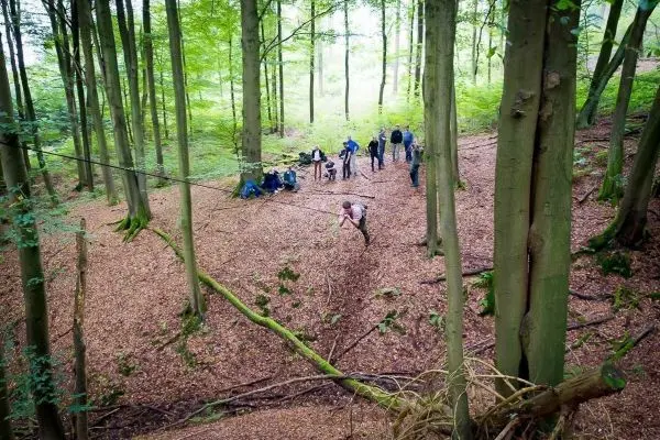 Selbstgebaute Seilquerung wird von einer Person überquert, während andere zuschauen