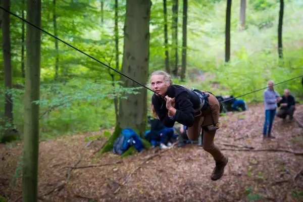 Überquert eine selbstgebaute Seilbrücke im Wald