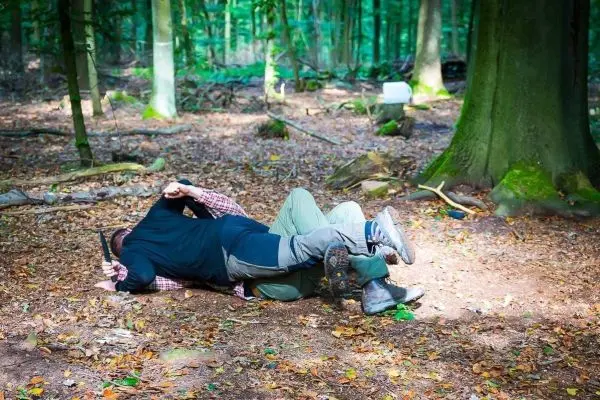 Zwei Personen im Wald in einer körperlichen Auseinandersetzung auf dem Boden