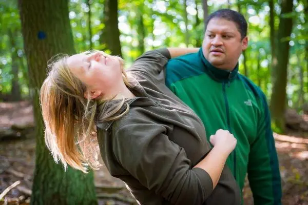 Zwei Personen in einem Wald, eine Person hält die andere am Arm
