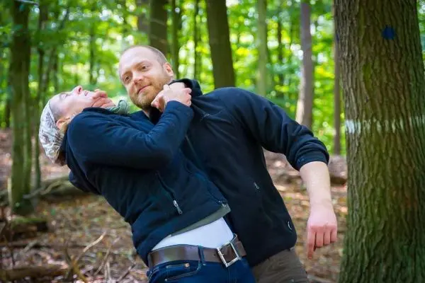 Zwei Personen in einer Waldumgebung führen eine Selbstverteidigungstechnik aus