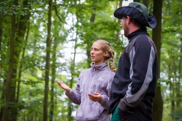 Zwei Personen stehen im Wald und unterhalten sich