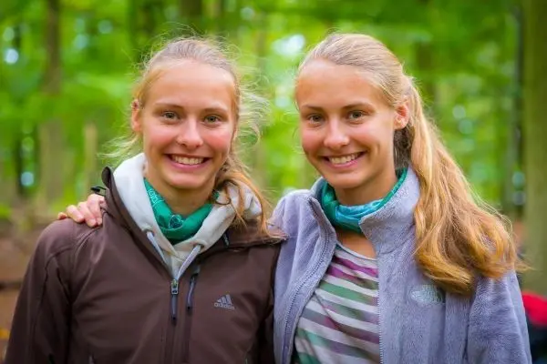 Zwei Personen stehen lächelnd nebeneinander im Wald