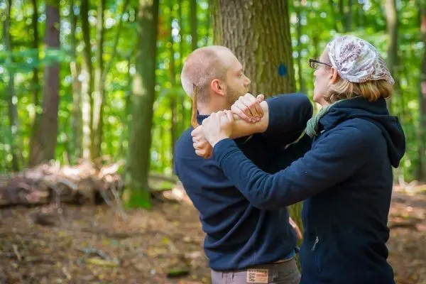 Zwei Personen üben eine Selbstverteidigungstechnik im Wald
