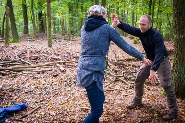Zwei Personen üben eine Technik zur Selbstverteidigung im Wald