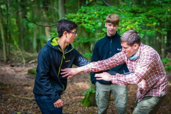 Zwei Personen üben eine Technik zur Selbstverteidigung im Wald
