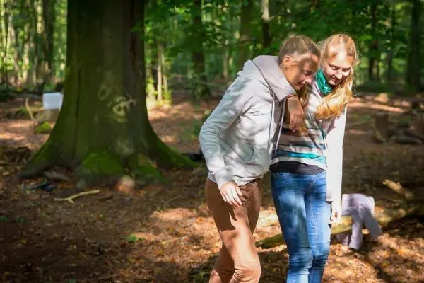 Zwei Personen unterstützen sich gegenseitig beim Gehen im Wald