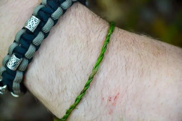 Armband aus geflochtenem Grünzeug und Paracord am Handgelenk sichtbar