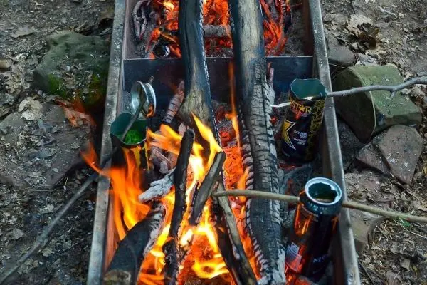 Kleine Flamme brennt zwischen Holzstücken in einer improvisierten Feuerstelle