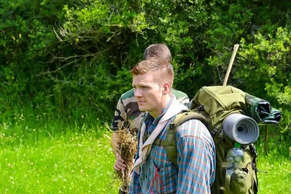 Mann mit Rucksack und Zunder in der Hand steht in der Natur
