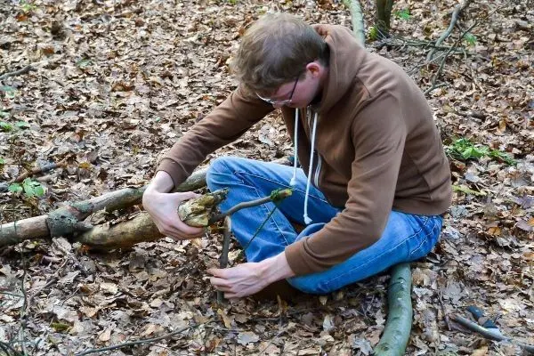 Person bearbeitet Holzstücke im Laub