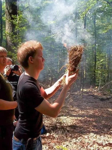 Zunder glimmt in der Hand, Rauch steigt auf