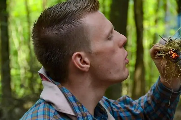 Zunder glimmt in der Hand, während Luft zugeführt wird