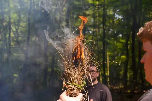 Zunder glimmt und kleine Flamme entsteht in der Hand