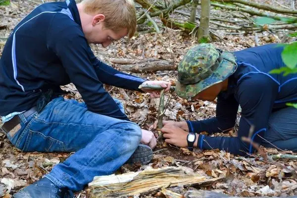 Zwei Personen bauen eine Feuerstelle im Wald auf