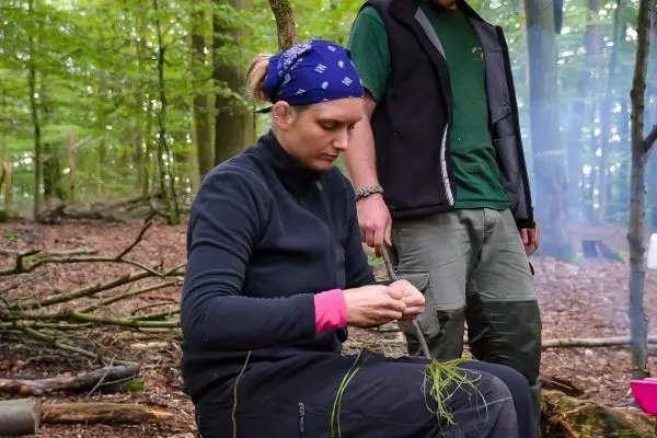 Frau bindet Pflanzenmaterial während einer Outdoor-Aktivität im Wald
